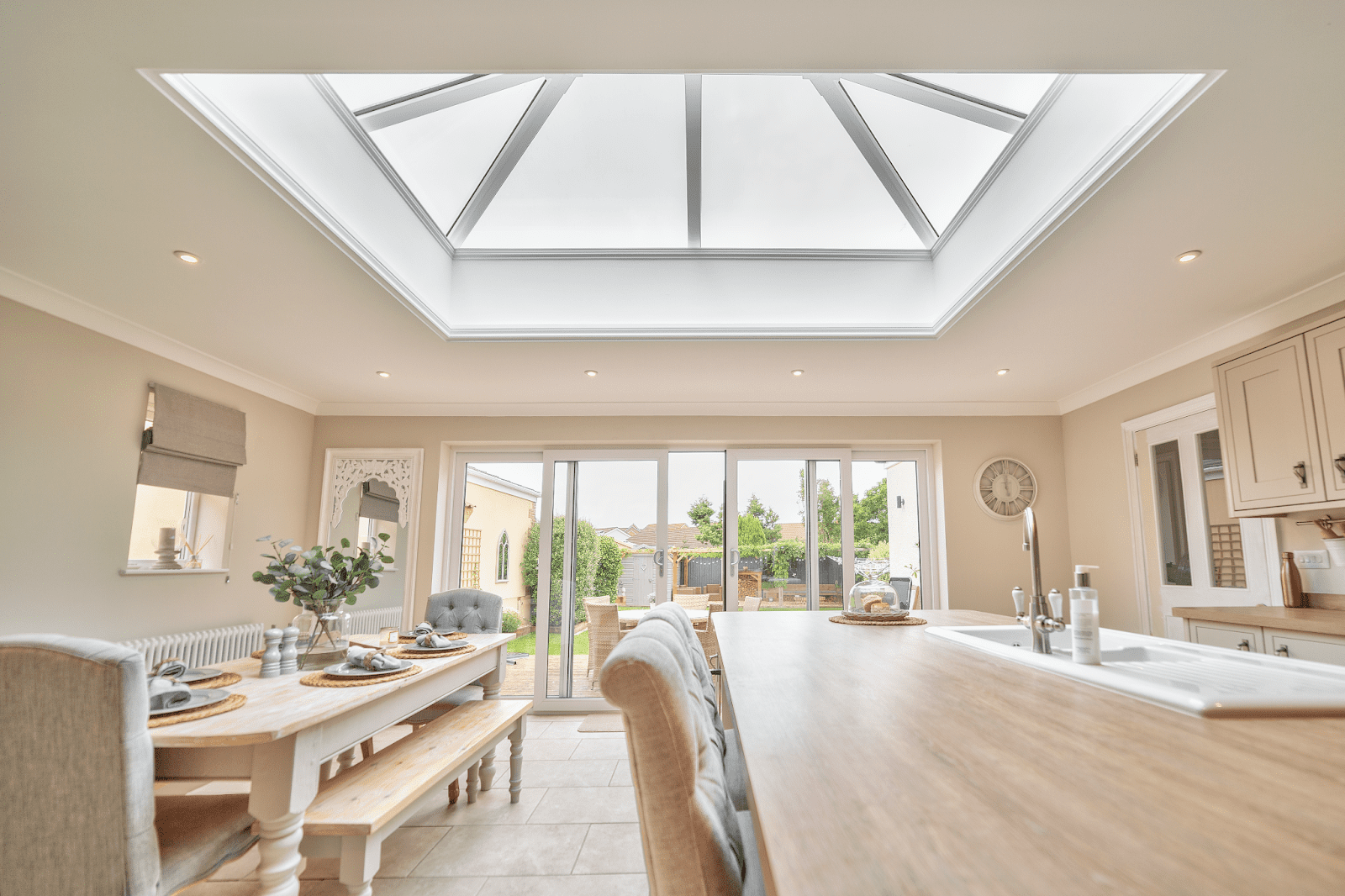 Spacious kitchen-diner with a large glass roof skylight, wooden dining table, and garden doors.