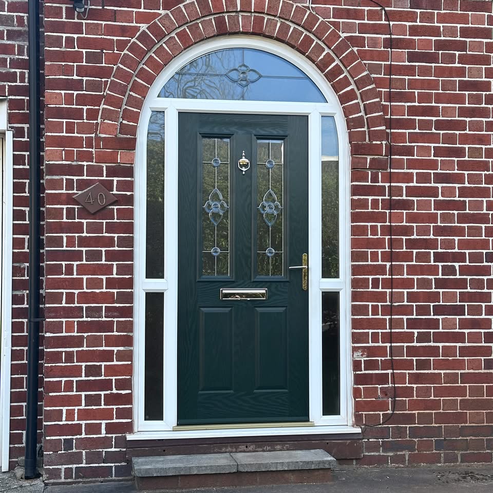 New green composite front door with ornate glazed panels, white frame and arch-top window, surrounded by red brickwork and side panels for added light