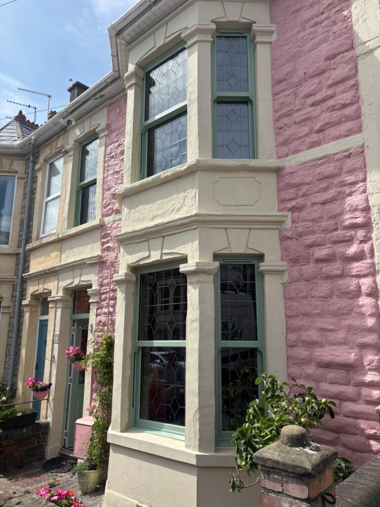 Green decorative glass sash windows of a pink Victorian terraced house